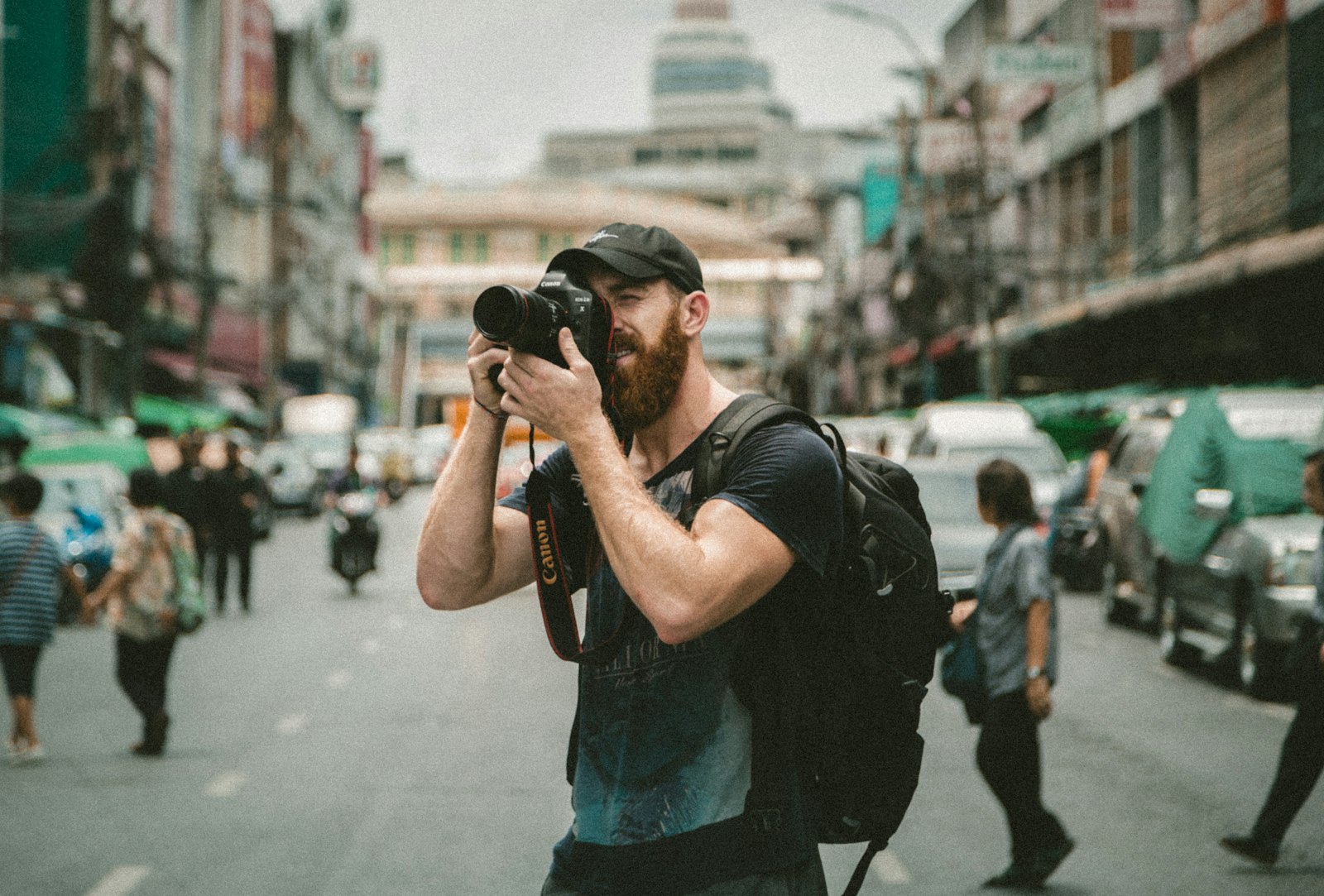 A photographer shooting with a DSLR, the street behind thrown out of focus
